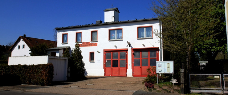 Das weiße Haus der Freiwilligen Feuerwehr Hartmannsdorf mit zwei großen roten Toren.