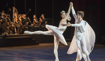 Balletttänzer in weißen Kostümen tanzen auf der Bühne.