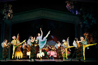 Viele bunt kostümierte Balletttänzer tanzen auf der Bühne, in der Mitte tanzt Alice