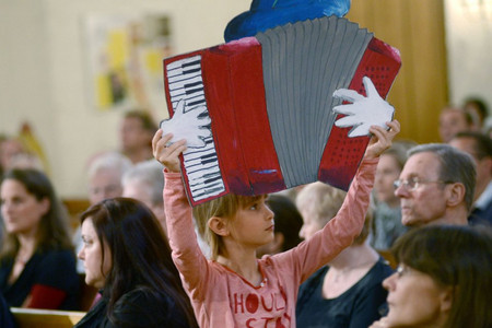 Ein Kind hält ein aus Pappe gebasteltes Akkordeon hoch