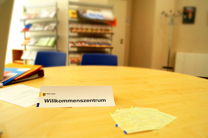 Ein runder Tisch im Willkommenszentrum mit einem Aufsteller mit der Aufschrift "Willkommenszentrum"