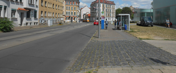 Gorkistraße mit schlechter Fahrbahn und teils gepflasterten Fußweg und mit einer Haltestelle.