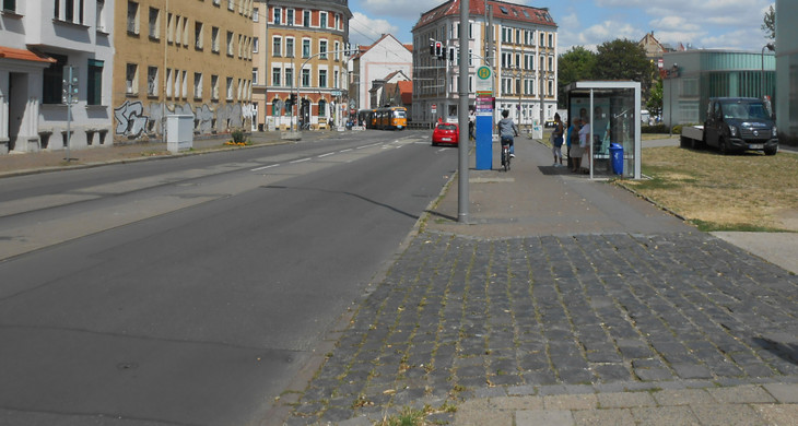 Gorkistraße mit schlechter Fahrbahn und teils gepflasterten Fußweg und mit einer Haltestelle.