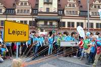 Leipziger mit OBM Burkhard Jung ziehen an einem Strang ein Ortsschild "Leipzig" in Richtung eines Schildes mit der Aufschrift "fair".