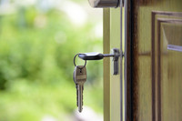 In einer braunen Wohnungstür steckt ein Schlüssel mit Schlüsselbund.