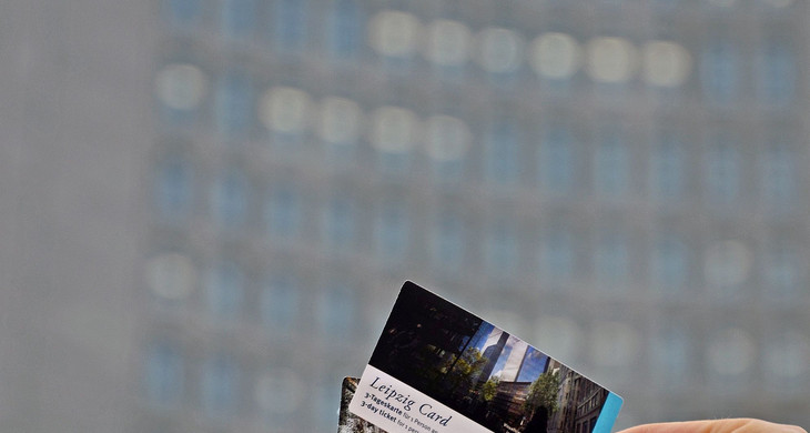 Eine Hand hält drei verschieden Leipzig Cards. Im Hintergrund ist das City-Hochhaus.