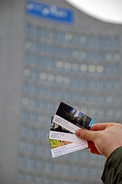 Eine Hand hält drei verschieden Leipzig Cards. Im Hintergrund ist das City-Hochhaus.