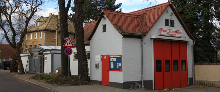 Ein sehr kleines Haus mit einem großen, roten Tor. Darüber ist ein Schild mit roter Aufschrift "Freiwillige Feuerwehr Rückmarsdorf".