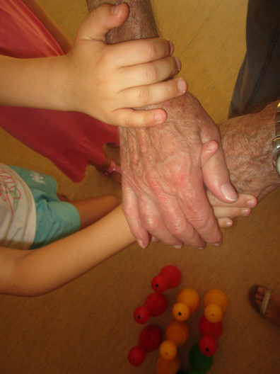 Zwei Kinderhände und die Hände einer älteren Person übereinandergelegt