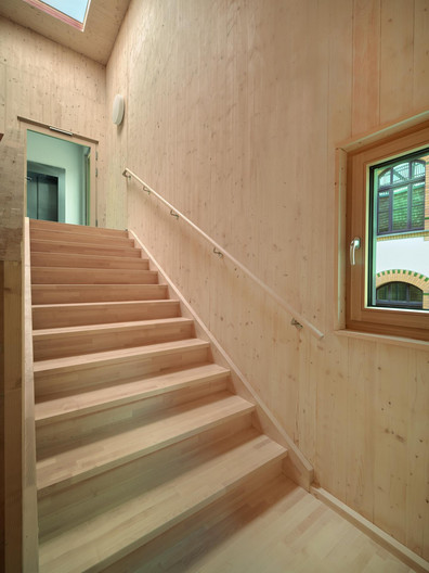 Blick auf eine Holztreppe und auf mit Sperrholzplatten verkleidete Wände.