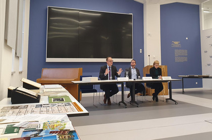 Ulrich Hörning, Emanuel Scobel und Marlen Schnurr sitzen in einem Raum an einem Tisch während einer Pressekonferenz.