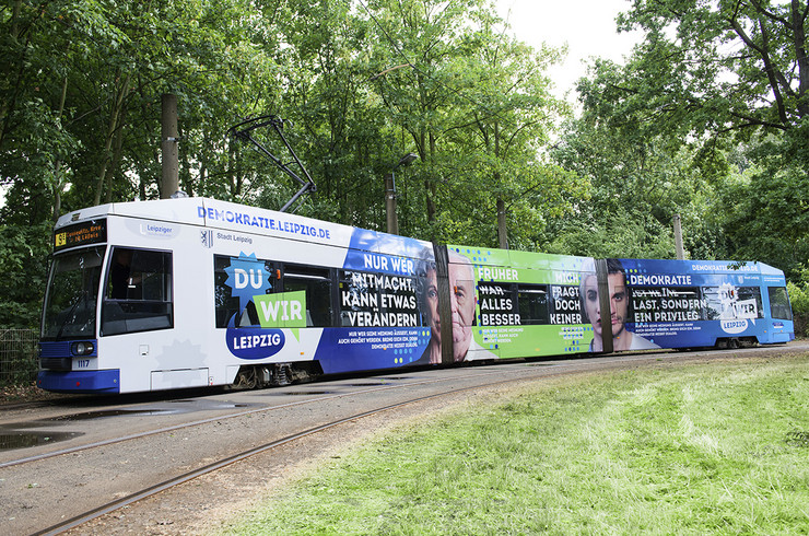 Eine Straßenbahn beklebt mit den Logos und Sprüchen zum Jahr der Demokratie in Leipzig.