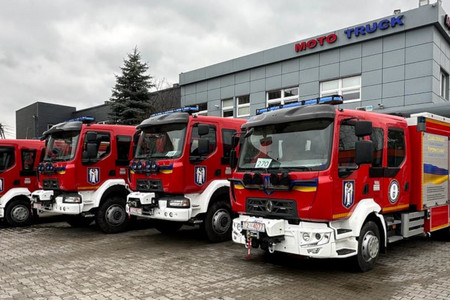vier rot-weiße Feuerwehrfahrzeuge stehen vor einer grauen Halle
