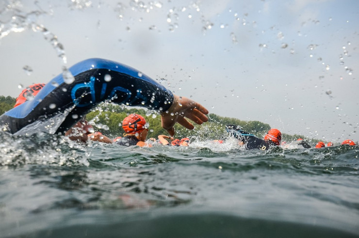 Sportler in Schwimmanzügen und mit Schwimmhauben beim Kraulen im Wasser
