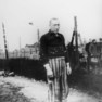 Männlicher Häftling in gestreifter Häftlingskleidung aus dem Konzentrationslager mit dunkler Jacke