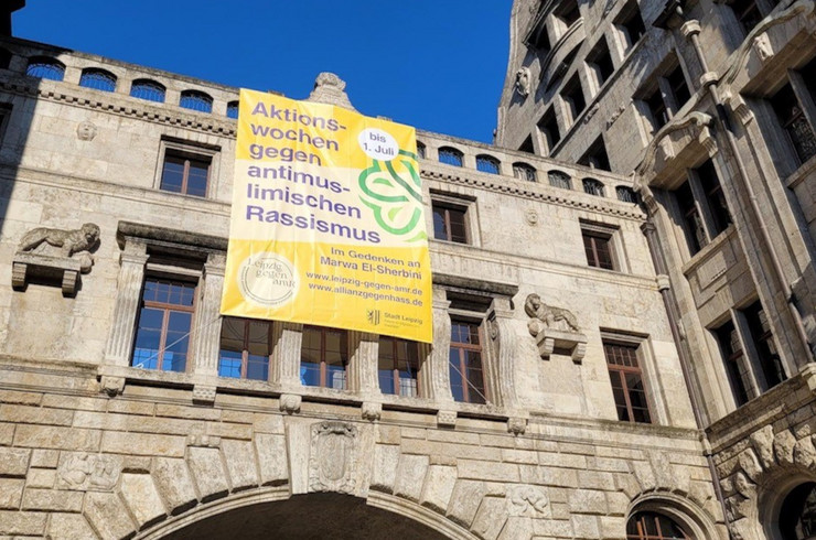 Am Übergang Neues Rathaus zum Stadthaus hängt ein gelbes Banner "Aktionswochen gegen antimuslimischen Rassismus"
