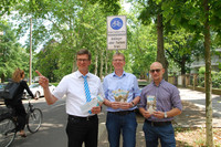 Drei Männer stehen mit Flyern in der Hand vor dem Verkehrsschild "Fahrradstraße"