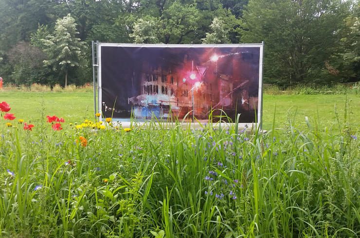 Großformatiges Kunstwerk auf einer Wiese im Clara-Zetkin-Park. Im Vordergrund blühen Blumen.