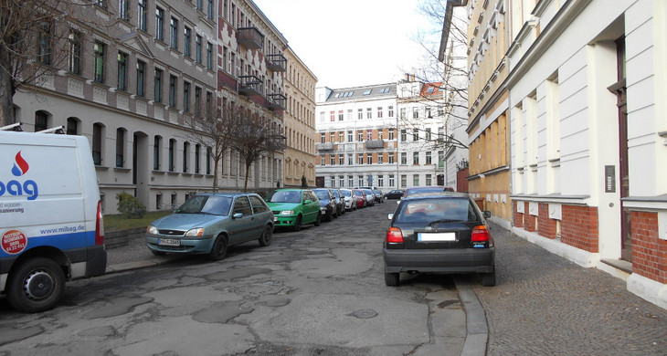 Stark gepflickte Straße mit parkenden Autos