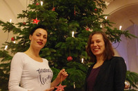 Fair geschmückter Weihnachtsbaum mit Mitarbeiterinnen davor