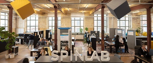 Blick in den Coworking-Space Spinlab: Ein Großraumbüro mit vielen Schreibtischen, an denen Männer und Frauen sitzen