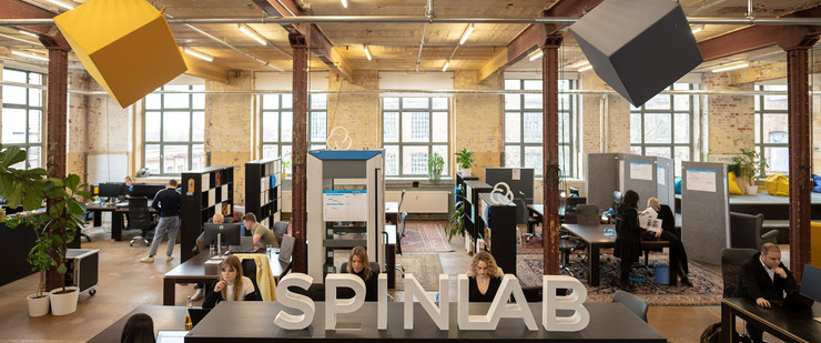 Blick in den Coworking-Space Spinlab: Ein Großraumbüro mit vielen Schreibtischen, an denen Männer und Frauen sitzen