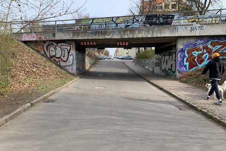 Eine Straße, die unter einer mit Graffiti bemalten Brücke verläuft