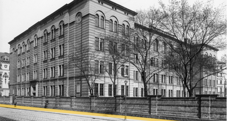 Schwarz-Weiß-Foto eines Schulgebäudes mit Mauer