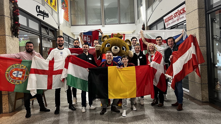 Mehrere Menschen mit ihren Landesflaggen freuen sich über die Ergebnisse des Final Draw zur Euro 2024.