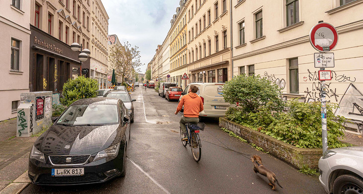 Blick in die Merseburger Straße mit parkenden Autos und einem Radfahrer