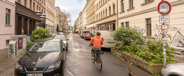 Blick in die Merseburger Straße mit parkenden Autos und einem Radfahrer