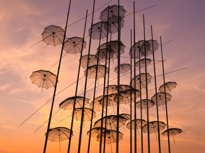 Kunstinstallation mit metallenen Schirmen vor dem Abendhimmel.