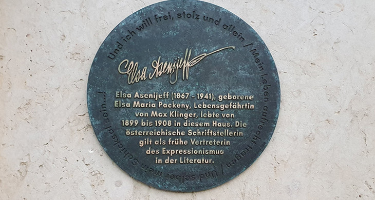 Runde metallene Gedenktafel für Elsa Asenijeff an einer Hauswand