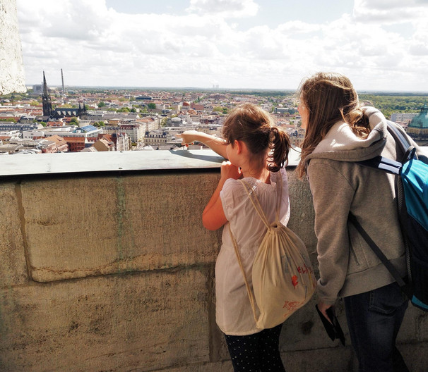 Zwei Mädchen im Schulalter schauen vom Rathausturm über die Stadt.