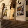 Gebäudeeingang aus Rundbögen, an denen ein Plakat mit dem Konterfei Bachs zur Bewerbung der Veranstaltung angebracht ist