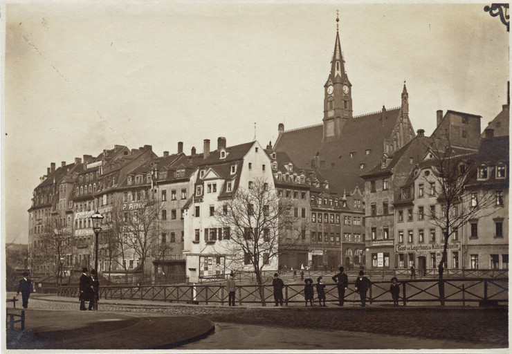 Auf der alten Fotografie stehen Personen an einem Geländer. Im Hintergrund steht die Matthäikirche.