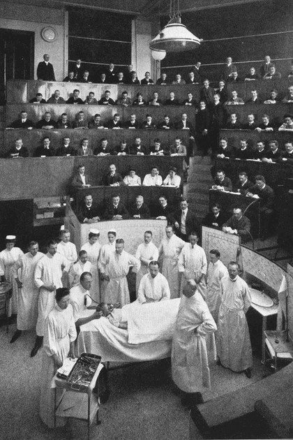 Szene aus dem Hörsaal mit Studenten und Lehrkräften bei einer chirurgischen Lehroperation im Jahre 1900.