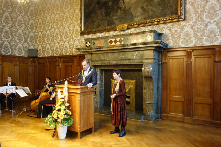 Oberbürgermeister Burkhard Jung steht hinter einem Stehpult und liest eine Rede vor. Neben ihm steht die Preisträgerin Dr. Heide Steer.