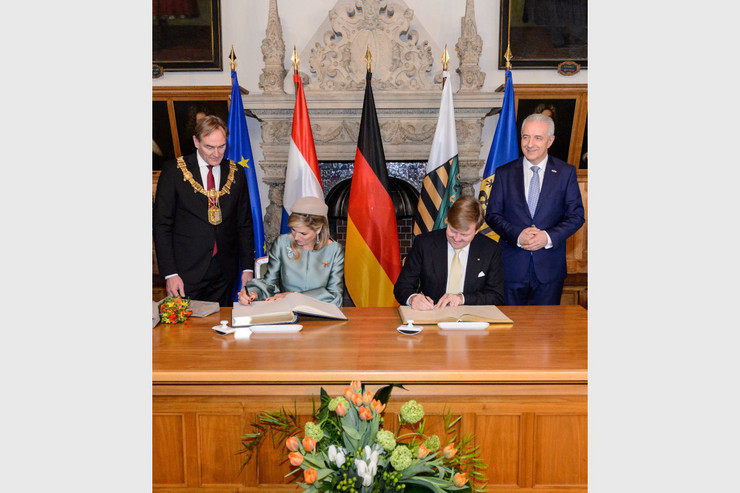 Das Königspaar der Niederlande, Königin Máxima und König Willem-Alexander, tragen sich ins Goldene Buch ein. Oberbürgermeister Burkhard Jung und der ehemalige Ministerpräsident Stanislaw Tillich stehen im Alten Rathaus neben dem Tisch mit dem Goldenen Buch.