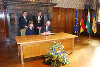 Bundespräsident Frank Walter Steinmeier sitzt an einem Tisch und trägt sich in das Goldene Buch der Stadt ein. Seine Ehefrau Elke Büdenbender sitzt neben ihm. Dahinter steht Oberbürgermeister Burkhard Jung,