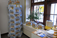 Mehrere Kartons, die Baby-Startpakete, stehen gestalpelt in der Ecke eines Büros.