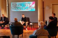 Enrico Lübbe, Thorsten Buß und Thomas Frank sitzen auf Sesseln vor einer Leinwand mit Text "Gefühlte Wahrheiten"
