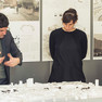 Zwei Männer und eine Frau schauen auf ein Stadtmodell und diskutieren.