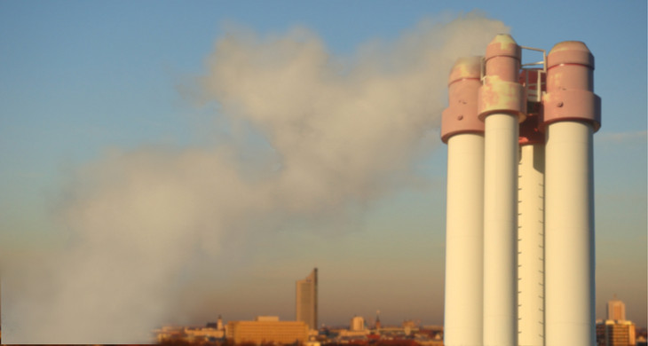 Rauchende Schornsteine einer fabrik, Silhouette von Leipzig im Hintergrund