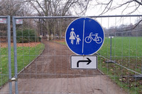 Abgesperrter Weg im Johannapark mit einem Verkehrsschild. Auf dem Schild sind Fußgänger und ein Fahrrad zu sehen und ein Pfeil für eine Umleitung