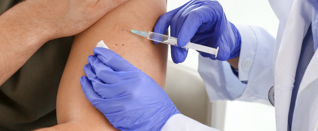 Arzt impft einen Mann mit einer Spritze in den Oberarm