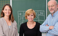 Zwei Lehrerinnen und ein Lehrer nebeneinander vor grüner Tafel.