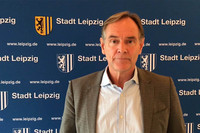 Oberbürgermeister Burkhard Jung vor einer Wand mit Stadt Leipzig Wappen