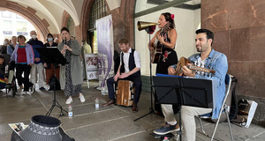 Eine Band von zwei Frauen und Männern spielen in der Leipziger Innenstadt vor Zuschauern und Zuschauerinnen.