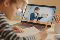Junge nutzt den Laptop um mit seinem Lehrer zu sprechen und schreibt nebenbei mit